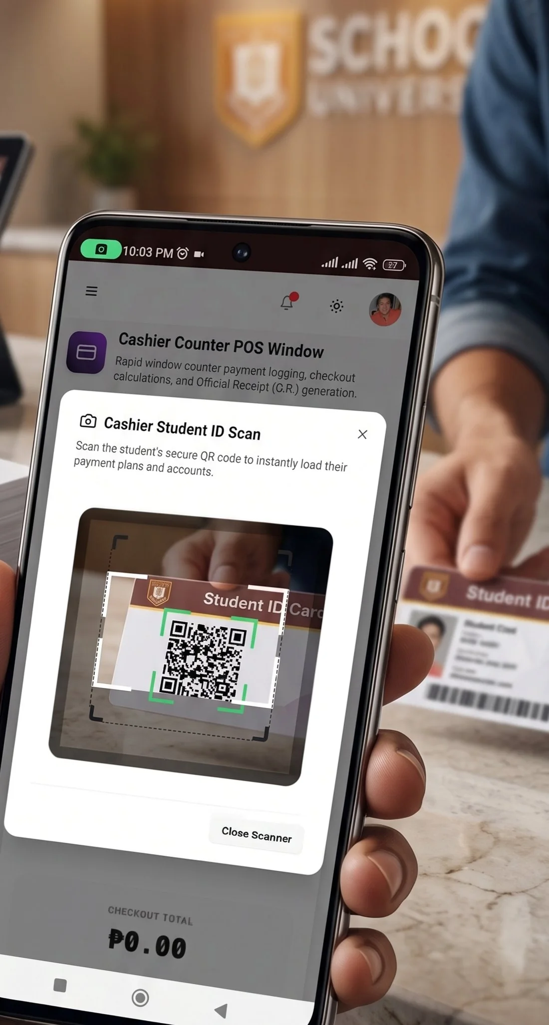 A cashier at a school counter holding a phone, its scanner framing the QR code on a learner's printed student ID card, with a stack of ID cards on the counter beside them